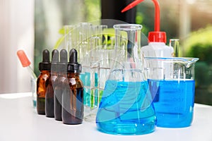 Blue experiment water in beaker and flask in chemistry science laboratory. Group of laboratory flasks with liquid inside.