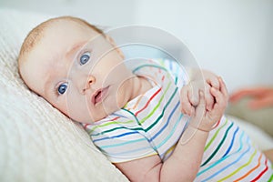 Blue eyed 3 months old baby girl in colorful clothes at home