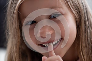 Blue-eyed blond girl laughs and shows the first tooth. children`s teeth, loss