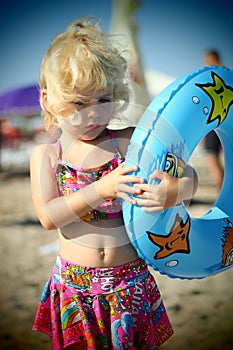 Blue eyed blond little girl on the beach in the summertime