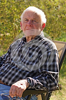 Blue eyed elderly man sits outside