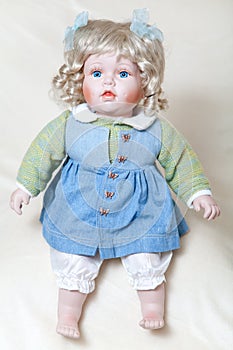 Blue-eyed girl doll sitting on soft light background