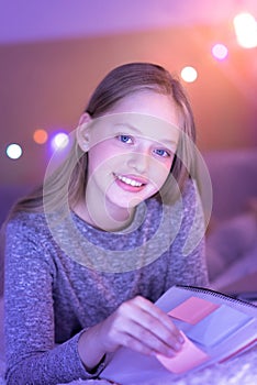 Blue-eyed girl smiling and holding her notebook