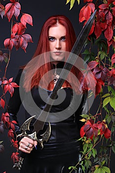 Blue Eyed Red Head Gothic Girl holding a fantasy sword among autumn vines