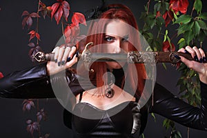 Blue Eyed Red Head Gothic Girl holding a fantasy sword among autumn vines