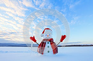 The blue eyed smiling snowman in red hat, gloves and plaid scarf holds the icicle in hand. Joyful cold winter morning.