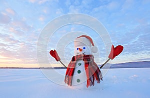 Blue eyed snowman. Sunrise enlightens the sky and clouds by warm colors. Reflecting on the snow. Mountains landscape.