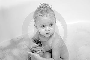 Blue eyes child in the bathing bucket looking at the camera and smiling. Small little cute sweet blonde boy bathes in a