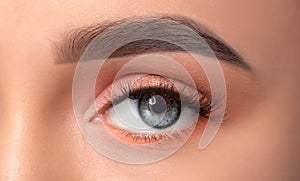 Blue eyes and eyebrows close-up. Portrait of a beautiful teenage girl with beautiful makeup, extended long eyelashes and healthy