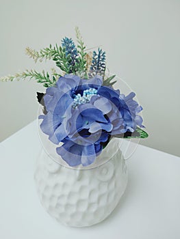 Blue fabric flowers arranged in white vases, used to decorate the living room.