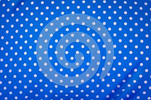 Blue fabric in polka dots pattern background. Modern textile texture. Detail of clothing