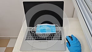 Blue face protection mask on a laptop on white office table