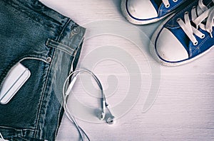 Blue faded jeans and blue sneakers on a white wooden background