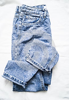 Blue faded mom jeans on a light background, top view. Fashion clothing