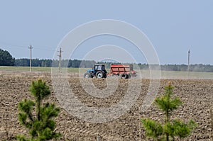 Blue farm tractor fertilize the field