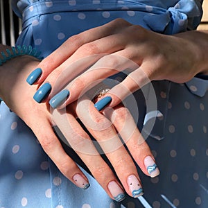 blue female manicure on nails close up