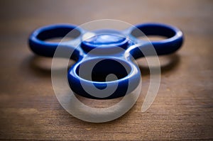 Blue fidget spinner isolated on wooden table.