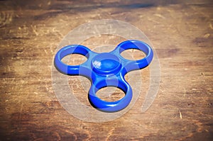 Blue fidget spinner isolated on wooden table.