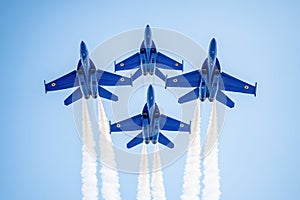 Blue fighter jets fly in formation with tricolor trails photo