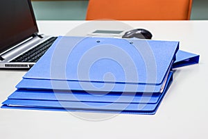 Blue file folder with documents and Notebook background on the white table