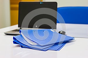 Blue file folder with documents and Notebook on the white table