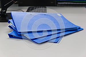 Blue file folder with documents on table in work office