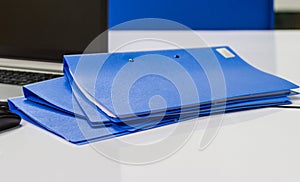 Blue file folder with documents and Notebook on the white table