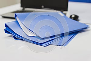 Blue file folder with documents and Notebook on the white table