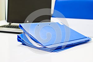 Blue file folder with documents and Notebook on the white table