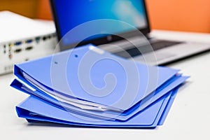 Blue file folder with documents and Notebook on the white table
