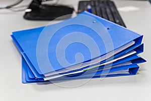 Blue file folder with documents on table in work office