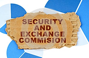 On the blue financial charts is a piece of cardboard that says - Security and Exchange Commision