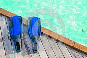 Blue fins for diving on a wooden pier against the background of azure water