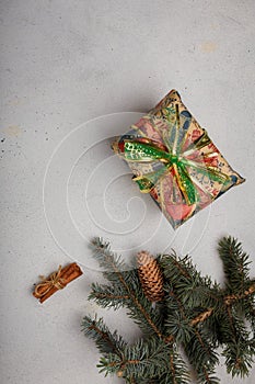 Blue fir tree branch with big cone, wrapped present box and cinnamon sticks on white wooden background. Christmas blank card, copy