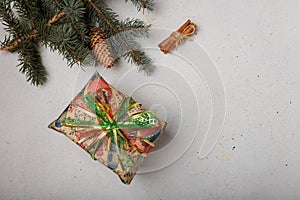 Blue fir tree branch with big cone, wrapped present box and cinnamon sticks on white wooden background. Christmas blank card, copy