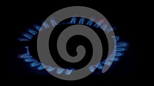 A blue fire lights up in the burner of the gas stove in complete darkness. The stove uses combustible or natural gas from the city