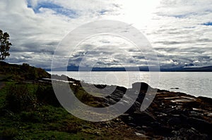 Blue fjord, sunhine and thick clouds