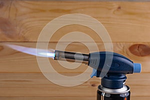 Blue flame with a manual gas burner on the wooden background. Close-up