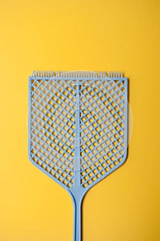 blue fly swatter on yellow background