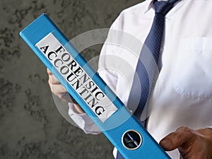 Blue folder with info about forensic accounting in the hands.
