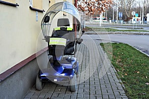 Blue four wheeled mobility scooter- electric wheelchair parked outside a house