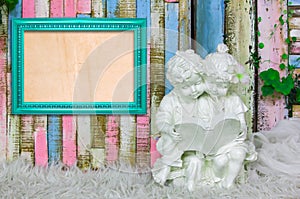 Blue frame and beautiful sculpture of boy and girl reading a book on colorful wooden background