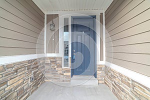 Blue front door of a home with sidelight and outdoor wall lamp at the entrance