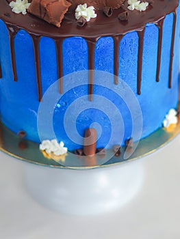 blue frosted icing cake with dark chocolate icing and mixed sweets as topping isolated on white background