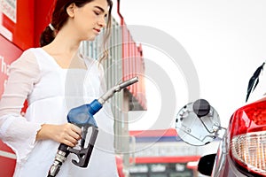 Blue fuel petrol pump nozzle against refueling auto car with petrol in beautiful young female traveler hand, beautiful young lady