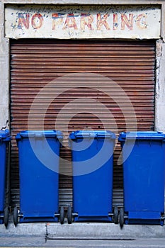 Blue garbage bins parked in a no parking zone