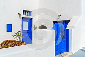 Blue gate and door of typical white Greek house in Oia village, Santorini island, Greece