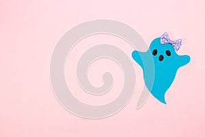 blue ghost with bow on right side pink background, copy space, creative halloween concept, flat lay, paper craft