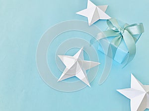 Blue gift box with blue ribbon on blue background with white star origami , copy space.