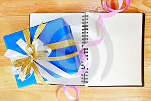 Blue gift box and colorful of ribbon on wood background.